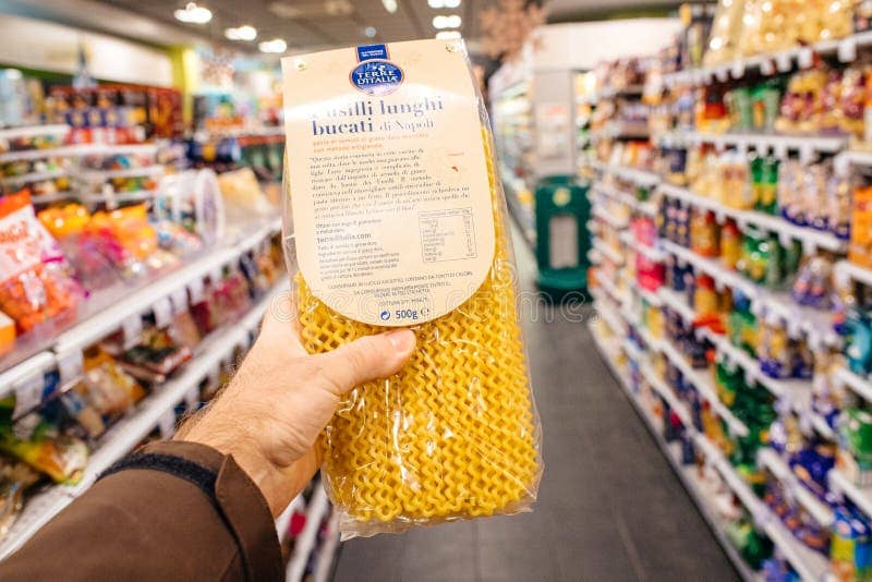 Holding a pasta package in a supermarket aisle