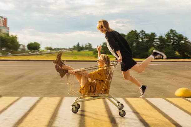 Two friends having fun with a shopping cart